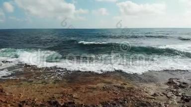 海浪拍打岩石悬崖海滩的空中拍摄。 波涛汹涌的海浪冲击着岩石海滩。 无人驾驶